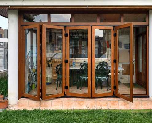 Cerramiento de porche con puertas plegables de aluminio serie 4000 de Alumarte lacado imitación embero y vidrio de seguridad 4+4 en Mutilva Baja